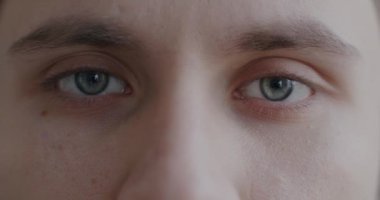 Adam kameraya bakarken, erkek gözlerinin yanıp sönen yavaş çekimde portresi. Yüz ifadesi ve görme konsepti.