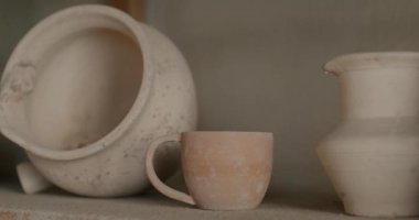 Geleneksel çömlek atölyesinde çeşitli seramik kaplar ve vazolar ahşap rafta. Küçük işletme ve yaratıcı hobi.