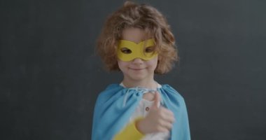 Gri arkaplandaki hayal kırıklığını ve anlaşmazlığı ifade eden el hareketlerini gösteren yavaş çekimde bir çocuk portresi. Çocukluk ve olumsuz duygu kavramı.