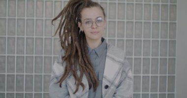 Rastalı saçlarıyla stüdyoda tek başına kameraya bakan yaratıcı genç bir kadının yavaş çekim portresi. İnsanlar ve bireysel tarz kavramı.