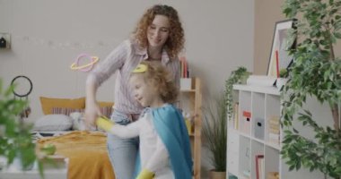 Süper kahraman kostümü giymiş oğluyla dans eden ve sonra da evde oğlanla kucaklaşan sevgi dolu bir anne. Annelik ve çocukluk kavramı.