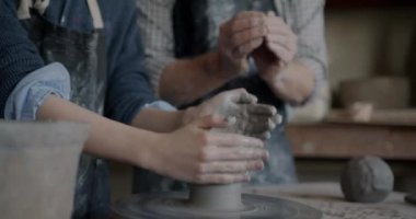 Yetişkin öğretmen stüdyoda talimat verirken çocukların çömlek çarkındaki kil kalıplarını yakın plan çekimleri. Çocukluk ve mesleki eğitim kavramı.