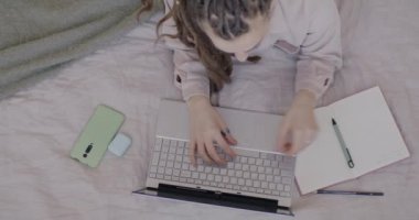 Rasta saçlı bir kızın evde internet kursuna yoğunlaşmış dizüstü bilgisayarla internetten ders çalışmasının en iyi görüntüsü. Uzaklık eğitimi ve e-öğrenme kavramı.