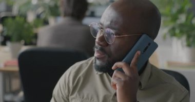 Afrika kökenli Amerikalı bir ofis çalışanı cep telefonuyla müşteriyle iş görüşmelerini konuşuyor. İletişim ve insan kavramı.