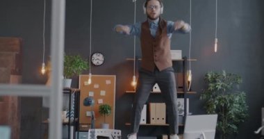 Masada dans eden, kulaklıklı ve ofiste eğlenen neşeli genç iş adamlarının yavaş çekimleri. İş yeri ve eğlence konsepti.