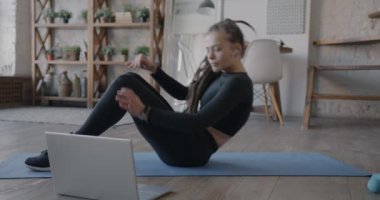 Çevrimiçi fitness maratonuna katılan sağlıklı genç bir kadın evde tek başına bilgisayar ve kulaklık eğitimi alıyor. Spor ve modern teknoloji kavramı.