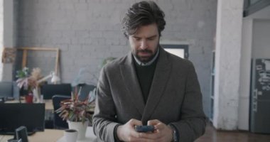 Yavaş çekimde, iş adamının internette akıllı telefon mesajları kullanarak ofiste yürümesini. Profesyonel iletişim ve iş adamı kavramı.