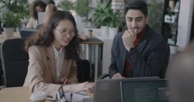 Erkek ve kadın meslektaşlar laptopa bakıp ofiste iş geliştirme hakkında fikir paylaşımı yapıyorlar. Şirket ve çalışan kavramı.