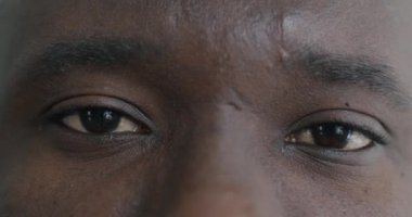 Afrika kökenli Amerikalı bir adam kameraya bakarken erkek gözlerinin yavaş çekim portresi. İnsanlar ve yüz ifadesi kavramı.