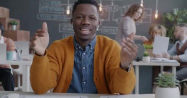 Sanal toplantıda konuşan ve el kol hareketi yapan Afrikalı Amerikalı iş adamının portresi ofiste online video görüşmesi yapan kameraya bakıyor. İş ve iletişim kavramı.