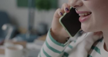 Cep telefonuyla konuşan genç bir bayanın bulanık ofiste çalışırken gülümsemesi. Cep telefonu iletişimi ve iş dünyası kavramı.