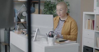Bilgisayarla çalışan Asyalı kadın bilişim uzmanı ofiste yazılım geliştirmeye odaklanmış. Modern teknoloji ve profesyonel işgal kavramı.