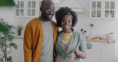 Yeni evde elinde anahtarlarla kameraya bakıp gülümseyen mutlu Afrikalı Amerikalı çift portresi. Gayrimenkul ve taşınma kavramı.