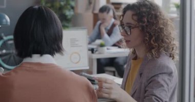 İş ortağıyla konuşan genç bir kadın bilgisayar ekranını işaret ederek şirket gelişimini tartışıyor. Profesyonel sohbet ve insan konsepti.