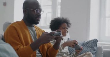 Afrikalı Amerikalı bir adam, sevimli oğluyla video oyunu oynuyor. Evinde çocukla eğleniyor. Aile yaşam tarzı ve oyun konsepti.