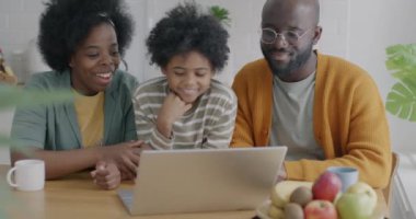 Anne baba ve çocuk bilgisayarla çevrimiçi video görüşmesi yapıyor evde sanal buluşmanın keyfini çıkarıyorlar. Aile yaşam tarzı ve iletişim konsepti.