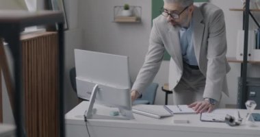 Ofiste çalışan deneyimli bir işadamı, bilgisayar ekranına bakarak not defteri yazıyor. Mesleki meslek ve iş dünyası kavramı.