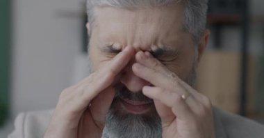 Yorgun, olgun iş adamının gözlerini ovuşturması, stresli ve yorgun hissetmesi. İş ve insan konsepti yüzünden sağlıklı sorunlar.