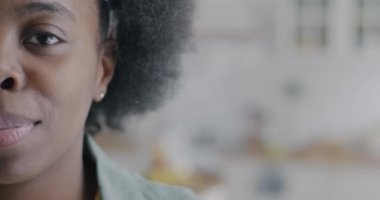 Güzel Afro-Amerikan bir kadının yavaş çekimde çekilmiş portresi bulanık arka planda gülümseyen kameraya bakıyor. İnsanlar ve duygu kavramı.