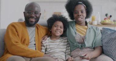 Afro-Amerikan kadın portresi. Kadın ve çocuk TV izlerken gülüyorlar. Evde kameraya bakarak konuşuyorlar. Aile ve kitle iletişim araçları.