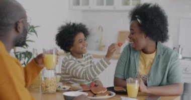 Sevgi dolu oğul anneyi çilekle besliyor. Annesiyle konuşuyor. Evde ailesiyle kahvaltı ediyor. Çocukluk ve annelik kavramı.