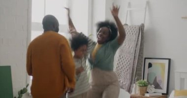 Oyuncu Afro-Amerikan insanları baba çocuk dans ediyor sonra yatağa düşüp gülüyorlar evde eğleniyorlar. Aile ve eğlence kavramı.