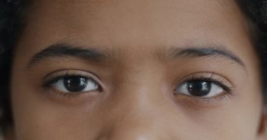 Afro-Amerikalı çocuğun yakın plan portresi büyük kahverengi gözleriyle kameraya bakıyor. Çocukluk ve insan yüzü ifadesi kavramı.