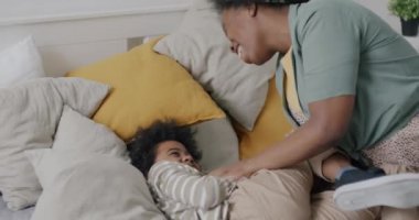 Afrika kökenli Amerikalı bir kadının, çocuğuyla evde eğlenen küçük bir çocuğu gıdıklaması. Aile yaşam tarzı ve ilişki kavramı.