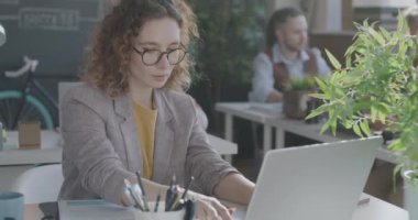 İş kadını belge okuyor ve birlikte çalıştığımız ofiste dizüstü bilgisayarla yazı yazıyor. Modern teknoloji ve iş adamı kavramı.