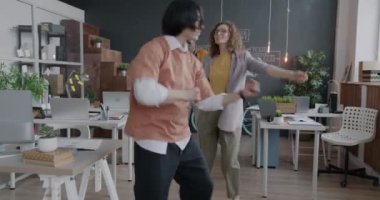Çok ırklı bir grup iş arkadaşı ofiste şirket partisinden zevk alarak dans ediyor. İş eğlencesi ve eğlence konsepti.
