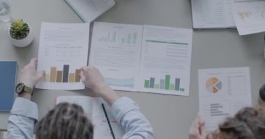Ofiste yapılan toplantı sırasında belgelere ve iş adamlarına bakan masa başı görüntüsü. Müzakere ve iş görüşmesi kavramı.