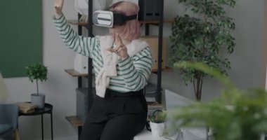 Sanal gerçeklik gözlüğü kullanan kadın ofis çalışanı iş arasında siber ortamın tadını çıkartıyor. Eğlence ve modern teknoloji konsepti.