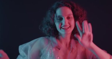 Karanlık arka planda neon ışıkta dans eden genç bir kadının portresi. Eğlence ve parti konsepti.