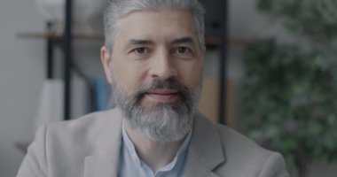 Ofis arkaplanındaki kameraya gülümseyen olgun iş adamının portresi. Pozitif duygu ve deneyimli profesyonel konsept.