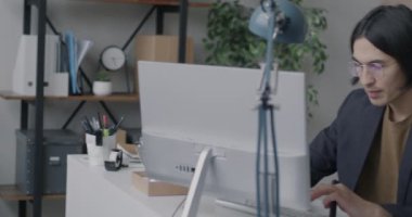 Asyalı ofis çalışanı ekranı işaret ederek mutlu bir gülümsemeyle başarılı bir işten zevk alıyor. İş ve olumlu duygu kavramı.