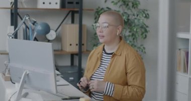Genç Asyalı kadın bilgisayarlı ve kulaklıklı internet üzerinden iş görüşmesi yapıyor. Sanal toplantı ve iletişim konsepti.