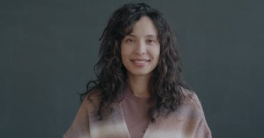 Orta Doğulu genç bir bayanın siyah arka planda gülümseyen el sallamasının yavaş çekim portresi. İletişim ve merhaba jest konsepti.