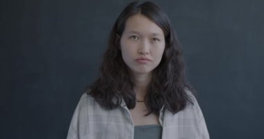 Asyalı mutsuz bir kızın portresi başını sallıyor, kollarını kavuşturuyor, yani siyah arka plana hayır diyor. Olumsuz duygu ve modern insan kavramı.