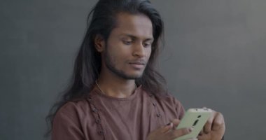 Siyah arkaplanda gülümseyen akıllı telefon ekranı kullanan neşeli Hintli adam. Modern teknoloji ve iletişim konsepti.