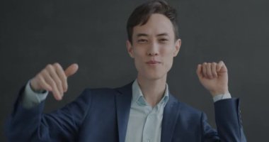 Takım elbiseli, dans eden, kameraya bakıp siyah arka planda eğlenen neşeli genç adamın yavaş çekim portresi. İnsanlar ve dans konsepti.