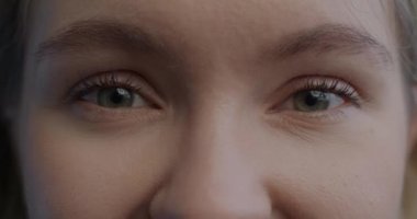 Güzel kızların güzel gözlerinin yakın plan portresi neşeli bir ifadeyle kameraya bakıyor. İnsan vücudu ve olumlu duygu kavramı..