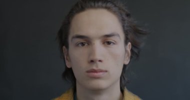 Siyah arka planda kameraya bakan sakin ve ciddi bir gencin portresi. İnsani duygu ve bireysellik kavramı.