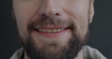 Siyah arkaplanda mutlu hisseden sakallı bir adamın gülümseyen erkek portresi. İnsanlar ve olumlu duygu kavramı.