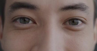 Genç adam kendini neşeli hissederken kameraya mutlulukla bakan erkek gözlerinin yakın plan portresi. Yüz ifadesi ve vücut parçası kavramı.