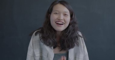 Aşırı mutlu Asyalı kadın portresi siyah arka planda mutluluğu ifade ediyor. Pozitif duygu ve heyecanlı insanlar konsepti.