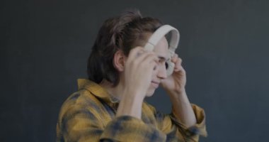 Kulaklık takan, müzik dinleyen ve siyah arka planda dans eden genç bir adamın yan görüntüsü. Gençlik kültürü ve eğlence kavramı.