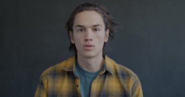 Şok olmuş genç bir adamın portresi. Siyah arka planda kameraya bakarken şaşkınlığını ifade ediyor. Duygusal ifade ve gerçek insan konsepti.