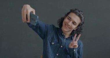 Neşeli İspanyol adam akıllı telefonuyla selfie çekiyor siyah stüdyo arka planında eğleniyor. Halk ve fotoğraf konsepti.
