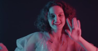 Karanlık arka planda neon ışıkta dans eden genç bir kadının portresi. Eğlence ve parti konsepti.