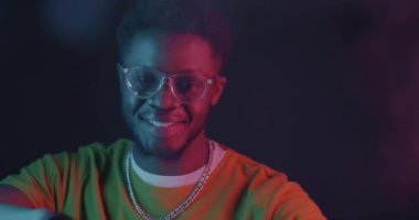 Siyah arka planda neon ışıkta dans eden Afrikalı Amerikalı bir adam. Gençlik kültürü ve modern eğlence konsepti.